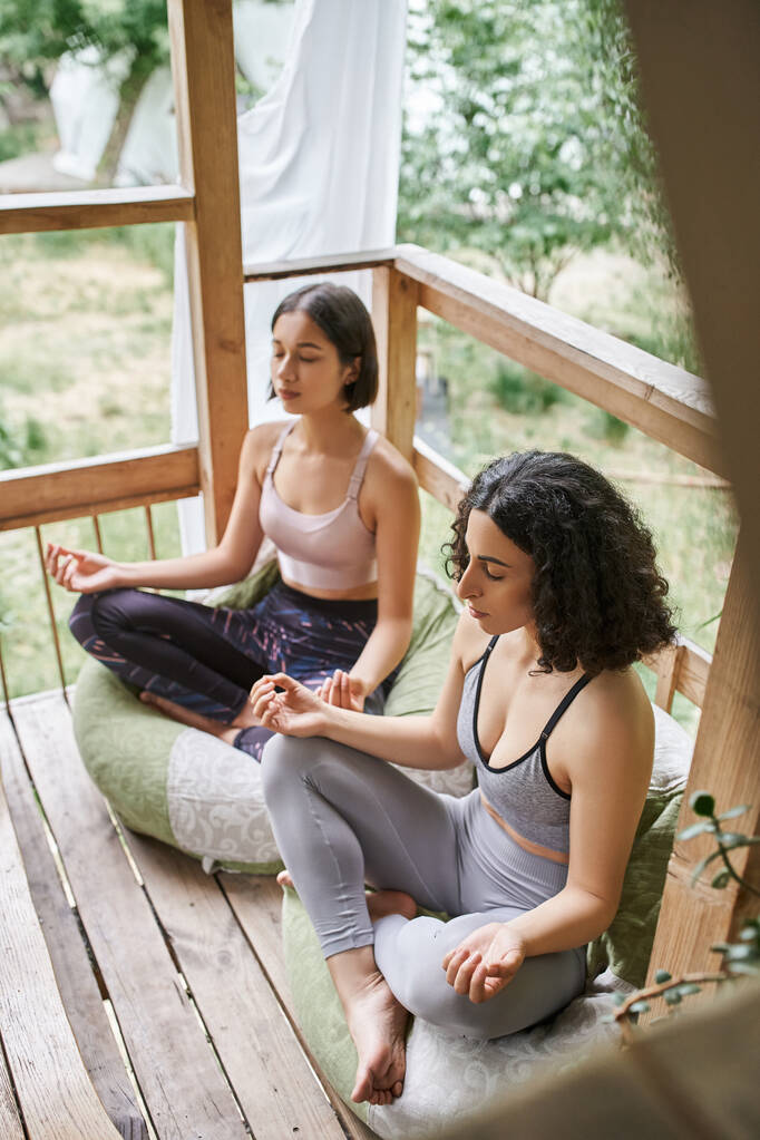 women retreat concept, multiethnic women meditating in lotus pose in cottage of retreat center - Photo, Image