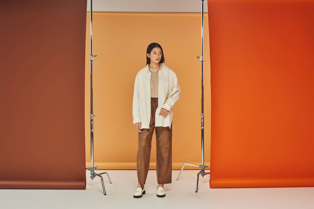 hübsche Asiatin posiert im Herbst-Outfit, Lederhose und Oberbekleidung, buntem Hintergrund - Foto, Bild