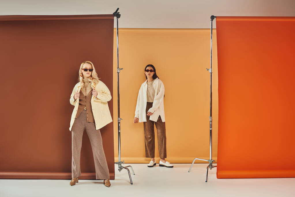 jesienna szafa, wielonarodowe kobiety w okularach przeciwsłonecznych i jesienna odzież wierzchnia na kolorowym tle - Zdjęcie, obraz