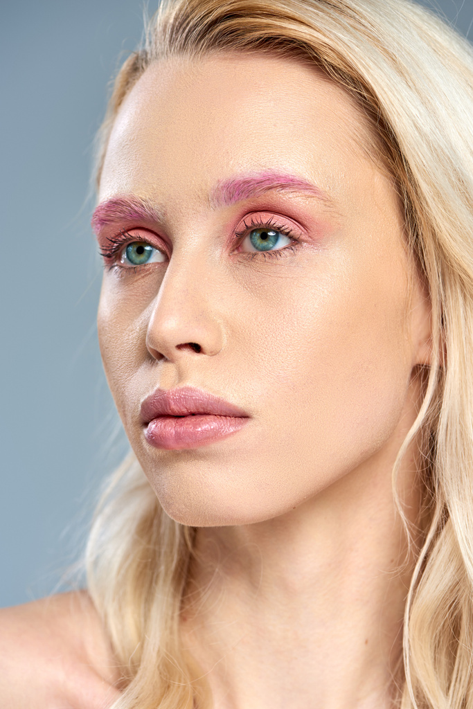 крупным планом, женщина с розовым макияжем глаз и голубыми глазами, отводящими взгляд на серый задник, женственная красота - Фото, изображение