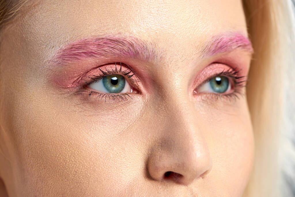 gedetailleerde foto van jonge vrouw met blauwe ogen en roze oogschaduwen die wegkijken, close-up - Foto, afbeelding