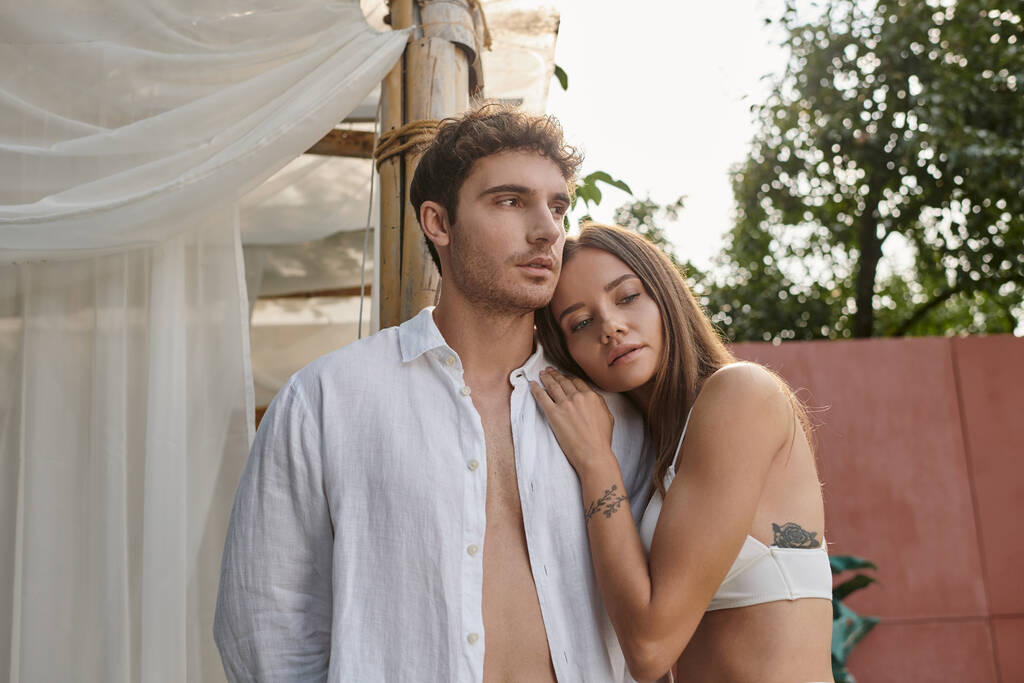 mujer tatuada apoyada en el hombro del novio en camisa blanca durante las vacaciones de verano, romance - Foto, imagen
