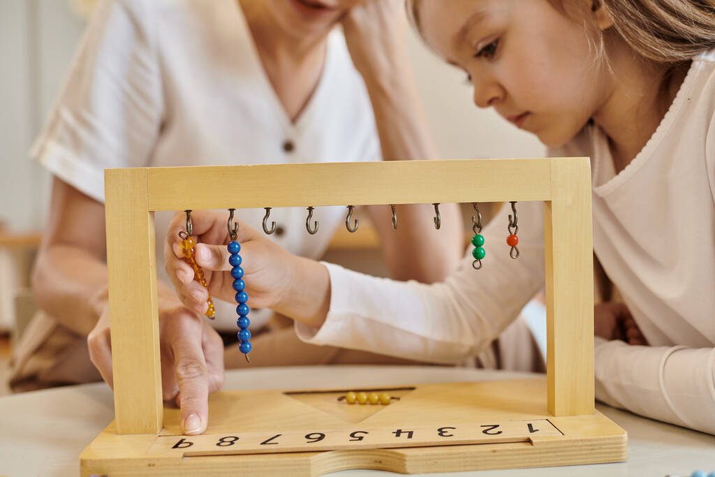 montessori concept, child playing with color bead stairs near teacher, wooden stand, close up - Photo, Image