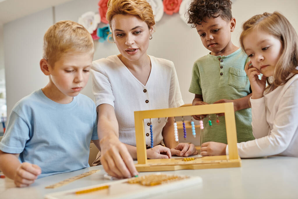 escuela montessori, niños multiculturales jugando con escaleras de cuentas de color cerca del maestro, diversidad - Foto, imagen