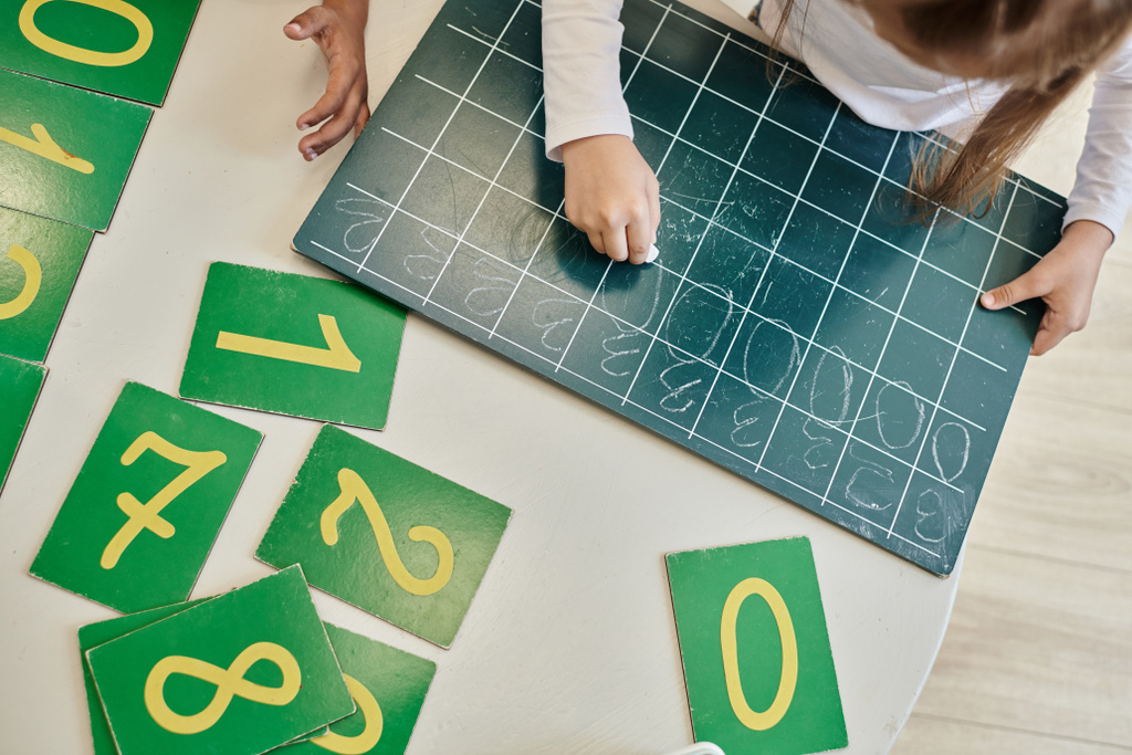 pohled na dívku, jak píše číslo nula na tabuli, učí se počítat ve škole Montessori - Fotografie, Obrázek