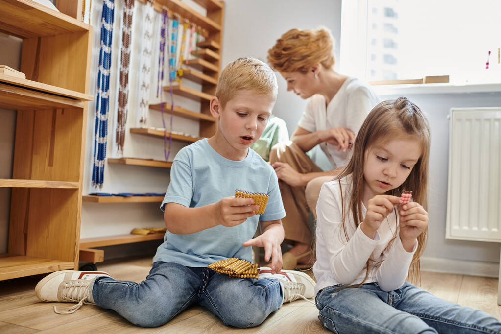 κορίτσι και αγόρι που κατέχουν Montessori χάντρες υλικό, καταμέτρηση, μάθηση μέσα από το παιχνίδι, παιδιά και δάσκαλος - Φωτογραφία, εικόνα