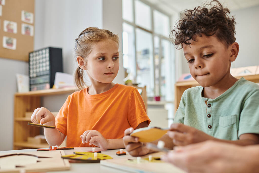 interrassische Kinder, die in der Schule mit didaktischem Montessori-Material spielen, lernen durch Spiel, Spaß - Foto, Bild