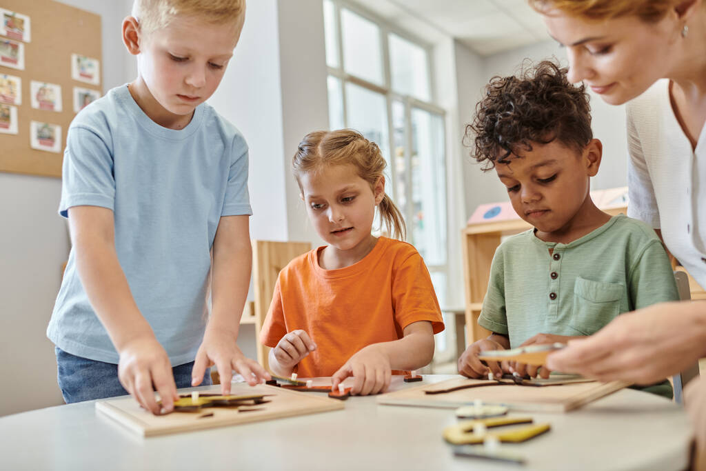 межрасовые дети играют с дидактическим Монтессори материал рядом с учителем в школе, учиться и играть - Фото, изображение