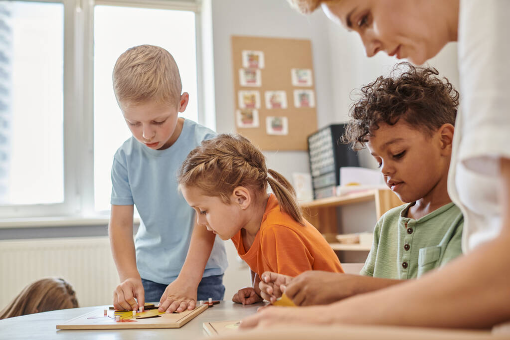 nauczyciel i wieloetniczne dzieci bawiące się materiałami dydaktycznymi w szkole montessori - Zdjęcie, obraz