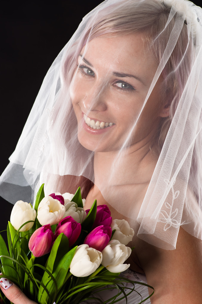 Χαμογελαστός νύφη με ένα μπουκέτο με τουλίπες με ένα πέπλο - Φωτογραφία, εικόνα