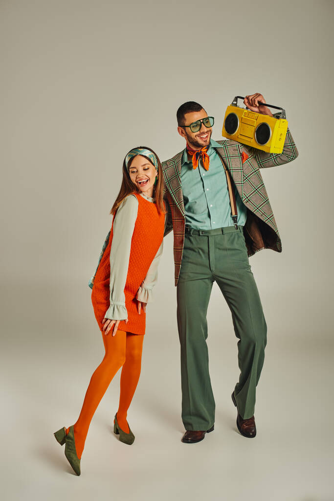 happy old-fashioned couple with yellow boombox dancing on grey, entertainment and retro lifestyle - Photo, Image