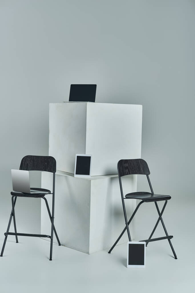 laptops and digital tablets with blank screen near white cubes and office chairs on grey backdrop - Photo, Image