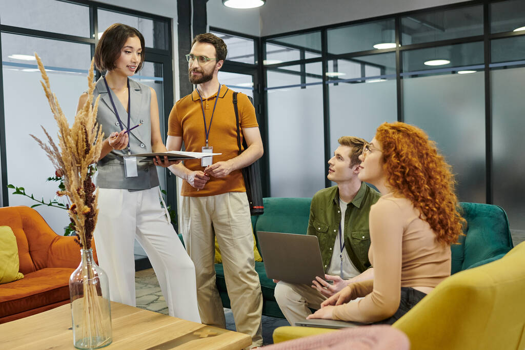 przedsiębiorczość, młody zespół prowadzący z papierami i laptopem rozmawiający z zespołem biznesowym w biurze - Zdjęcie, obraz