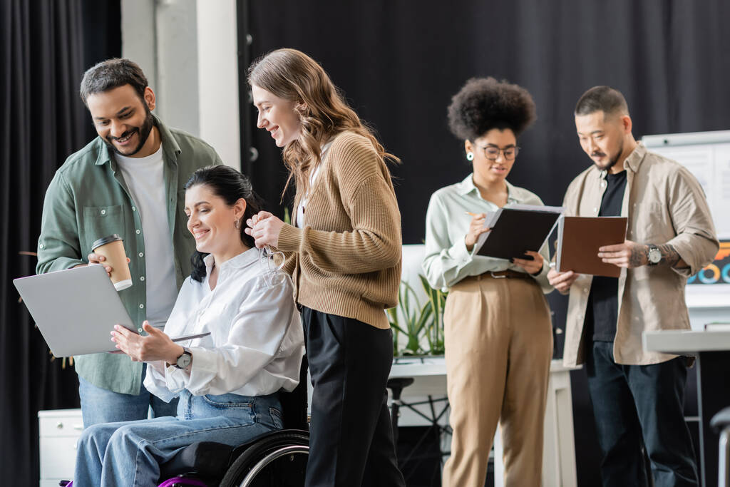 femme handicapée en fauteuil roulant discuter projet de démarrage sur ordinateur portable avec des collègues interracial heureux - Photo, image