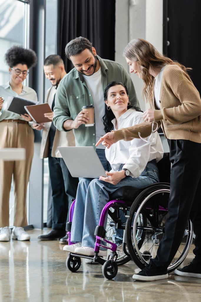 niepełnosprawna kobieta na wózku inwalidzkim omawia projekt startupowy ze szczęśliwym zespołem międzyrasowym w pracy - Zdjęcie, obraz