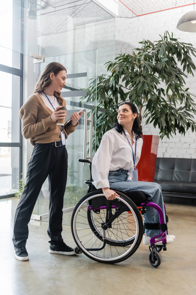 Inklusionskonzept, fröhliche Frau bei Kaffee und Gespräch mit behinderter Kollegin im Rollstuhl - Foto, Bild