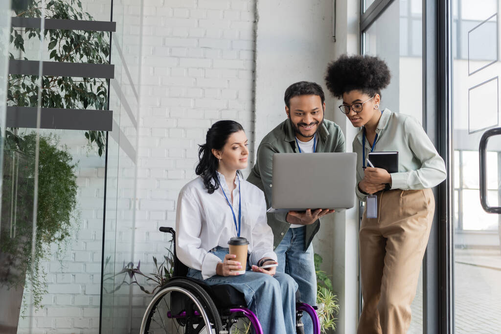 grupo tiro de empresários diversos, mulher com deficiência em cadeira de rodas olhando para laptop com colegas de trabalho - Foto, Imagem