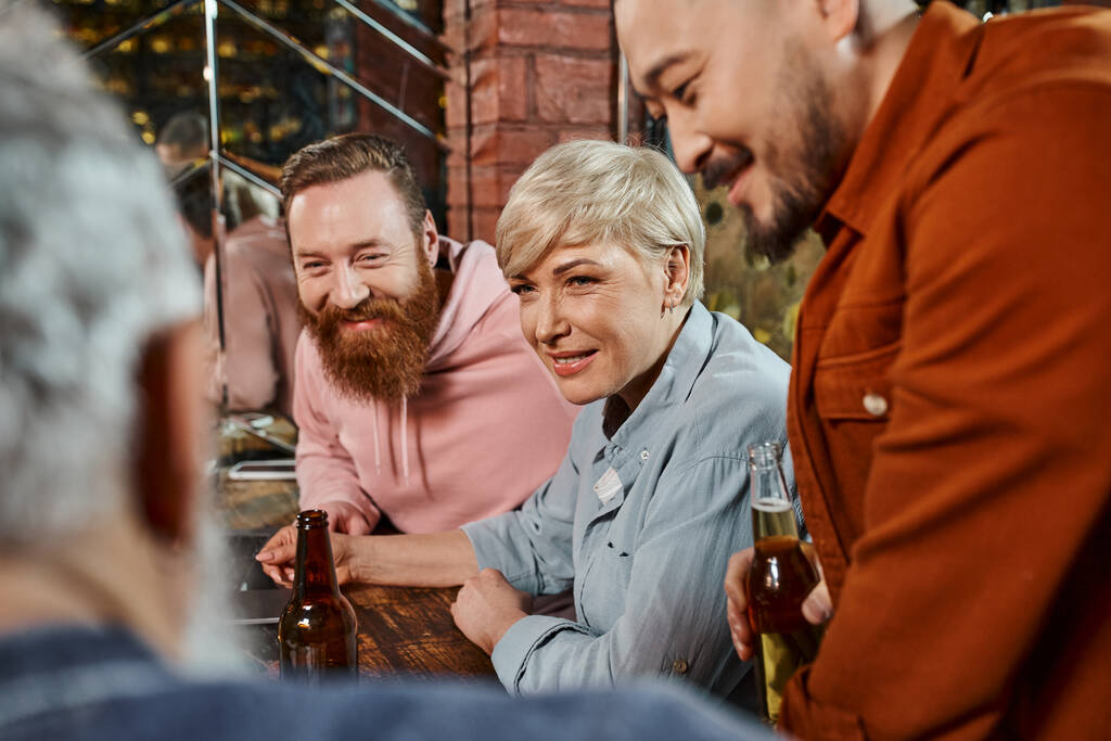 sonrientes compañeros de trabajo multiculturales que escuchan a un colega borroso mientras planean un nuevo proyecto en el pub - Foto, Imagen