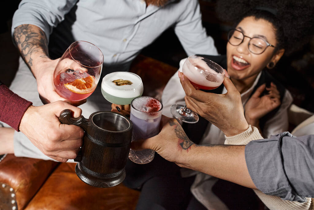 aufgeregte afrikanisch-amerikanische Frau klimpert Cocktailgläser mit Kollegen in Bar, Firmenparty - Foto, Bild