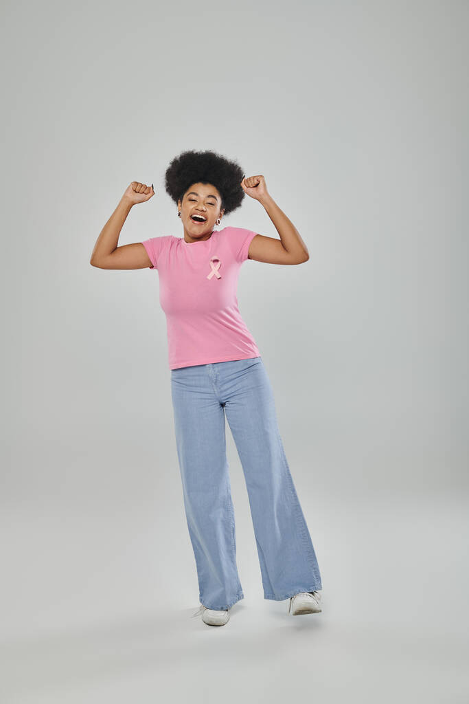 conciencia de cáncer de mama, concepto libre de cáncer, alegría, mujer afroamericana con cinta rosa en gris - Foto, Imagen