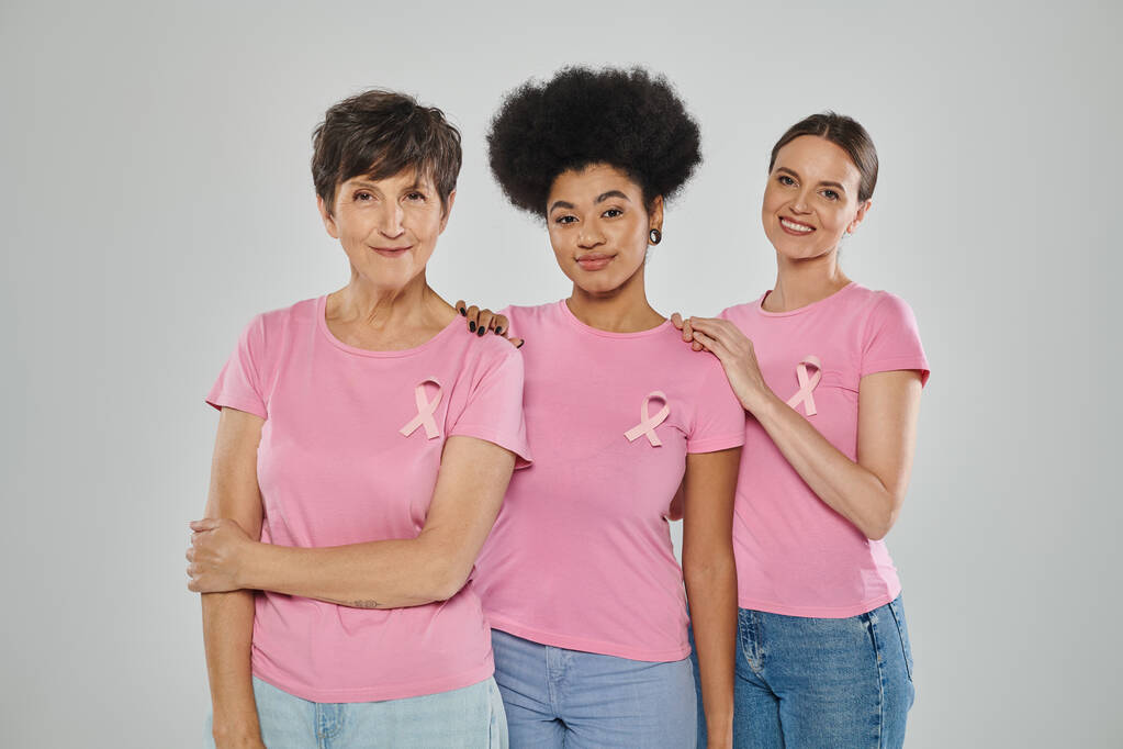 świadomość raka piersi, szczęśliwe wielokulturowe kobiety uśmiechnięte na szarym tle, różne pokolenia - Zdjęcie, obraz