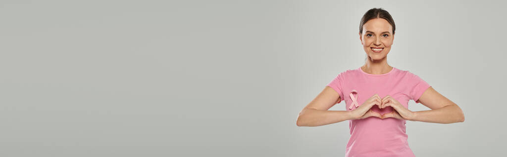 mulher feliz com fita rosa, fundo cinza, consciência de câncer de mama, mostrando sinal de coração, banner - Foto, Imagem