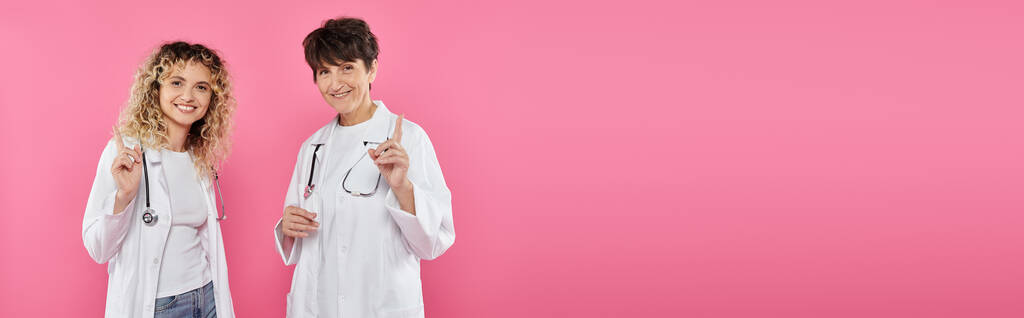 female doctors in white coats warning on pink backdrop, joy, breast cancer awareness, women, banner - Photo, Image