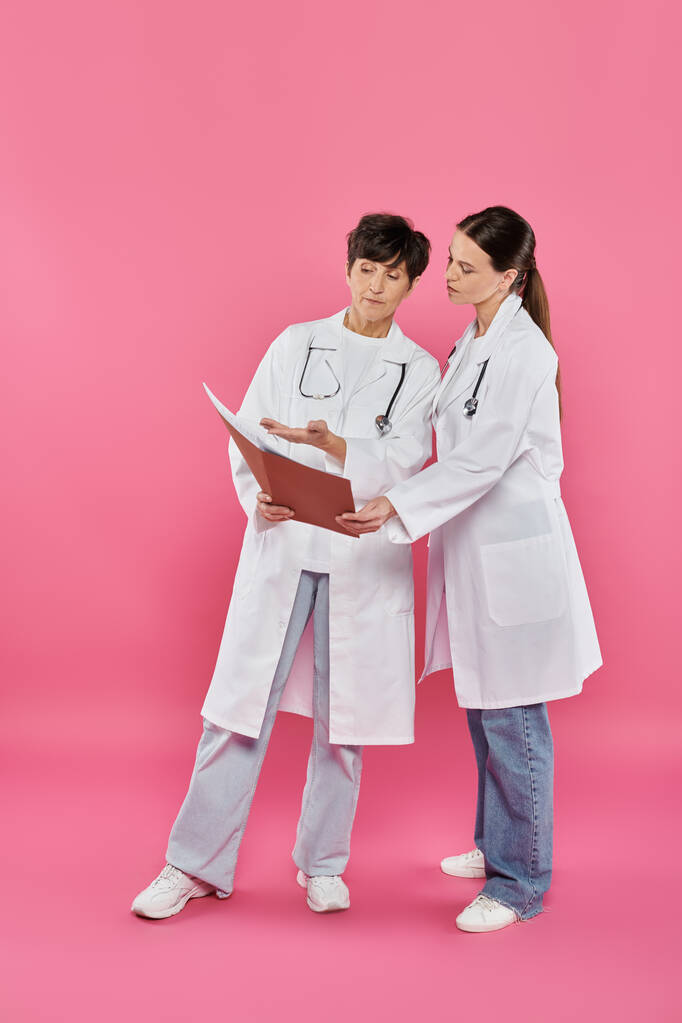 онкологи, жінки-лікарі, які дивляться на папку, медичні записи, обізнаність про рак молочної залози, кампанія - Фото, зображення