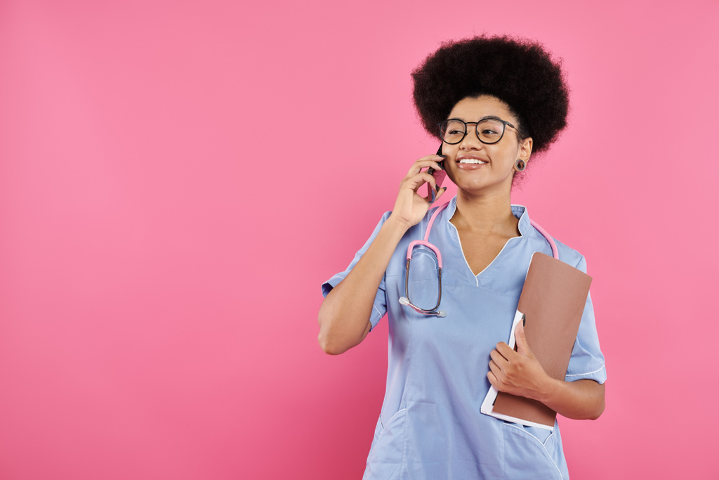 conciencia del cáncer de mama, médico afroamericano, oncólogo feliz con la carpeta hablando en el teléfono inteligente - Foto, imagen