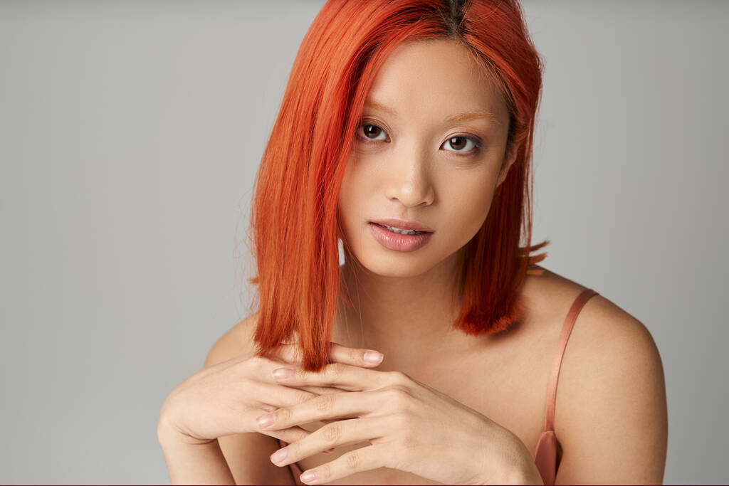 portré hipnotizáló fiatal ázsiai nő tökéletes bőr nézi kamera szürke háttér - Fotó, kép