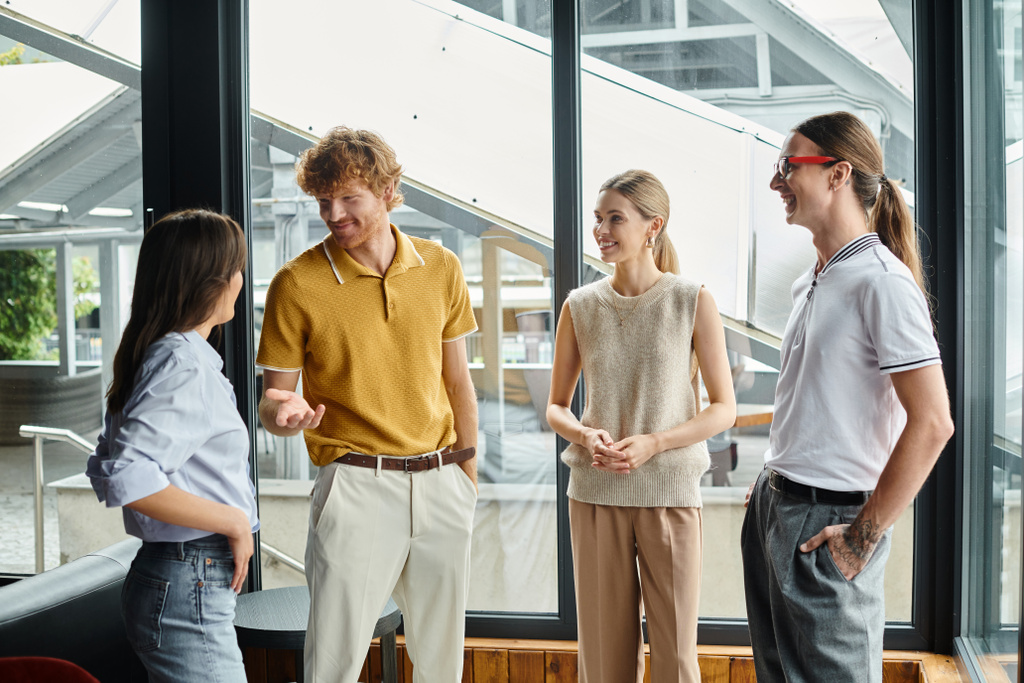 four coworkers in business casual clothing happily chatting to each other, coworking concept - Photo, Image