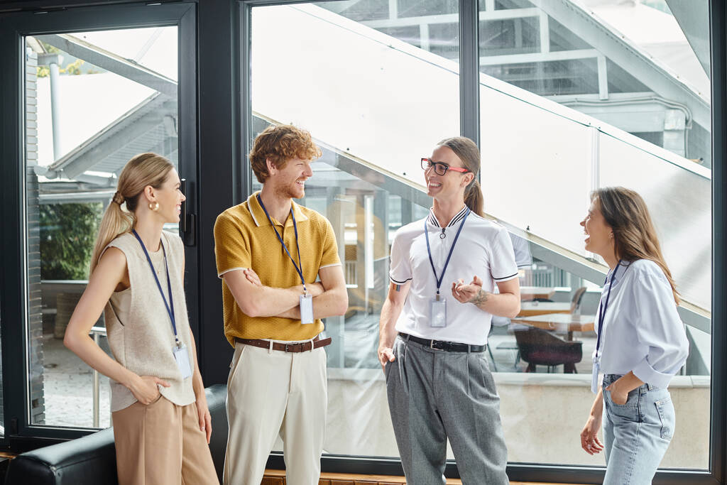 quatro jovens funcionários em trajes casuais inteligentes sorrindo sinceramente discutindo o trabalho, conceito de coworking - Foto, Imagem
