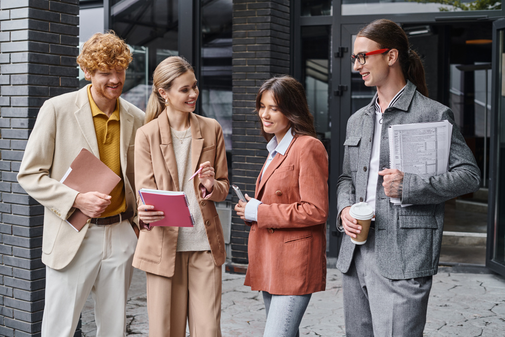 neljä kollegaa keskustelevat paperitöistä ulkona pitäen matkapuhelinta ja kahvikuppia, coworking - Valokuva, kuva