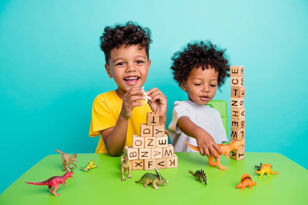 Πλήρης φωτογραφία μεγέθους του αξιολάτρευτο μικρά αγόρια παίζουν ξύλινα κύβους πυραμίδα σωρό διασκεδάζουν ντυμένοι κομψό ντύσιμο απομονώνονται σε φόντο κυανό χρώμα. - Φωτογραφία, εικόνα