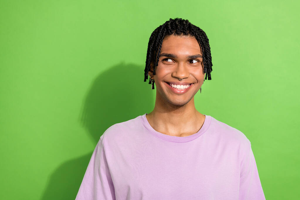 Photo of cheerful minded young man beaming smile look interested empty space isolated on green color background. - Photo, Image