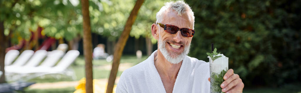 conceito de retiro de bem-estar, homem maduro feliz em óculos de sol desfrutando refrescante coquetel, banner - Foto, Imagem