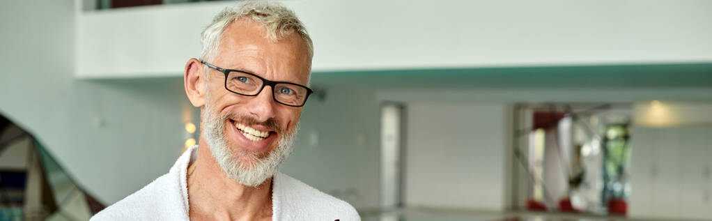 concept de retraite bien-être, homme mature joyeux en robe blanche et lunettes dans le centre de spa, bannière - Photo, image