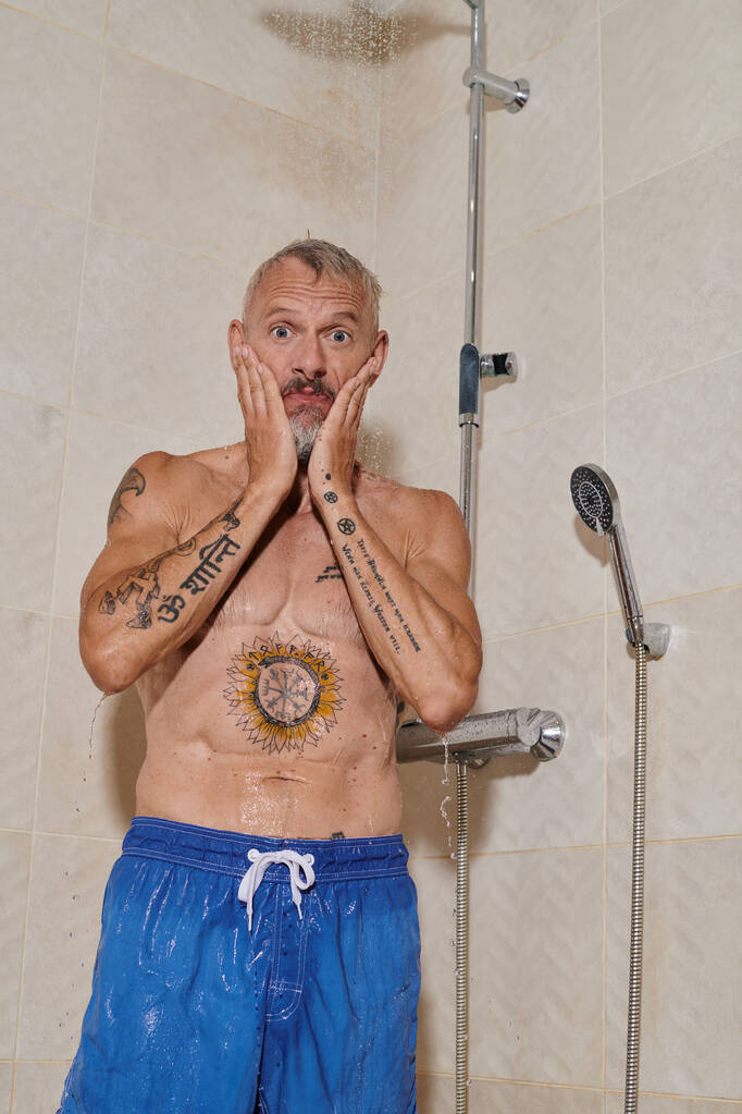 αστείο μεσήλικας άνδρας με τατουάζ λαμβάνοντας ντους και πλύσιμο προσώπου, προσωπική υγιεινή - Φωτογραφία, εικόνα