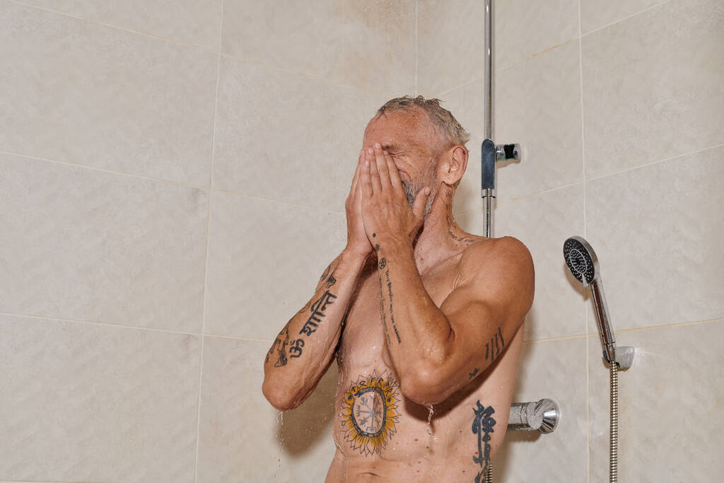 bez koszuli mężczyzna w średnim wieku z tatuażami biorąc prysznic i mycie twarzy, higieny osobistej - Zdjęcie, obraz