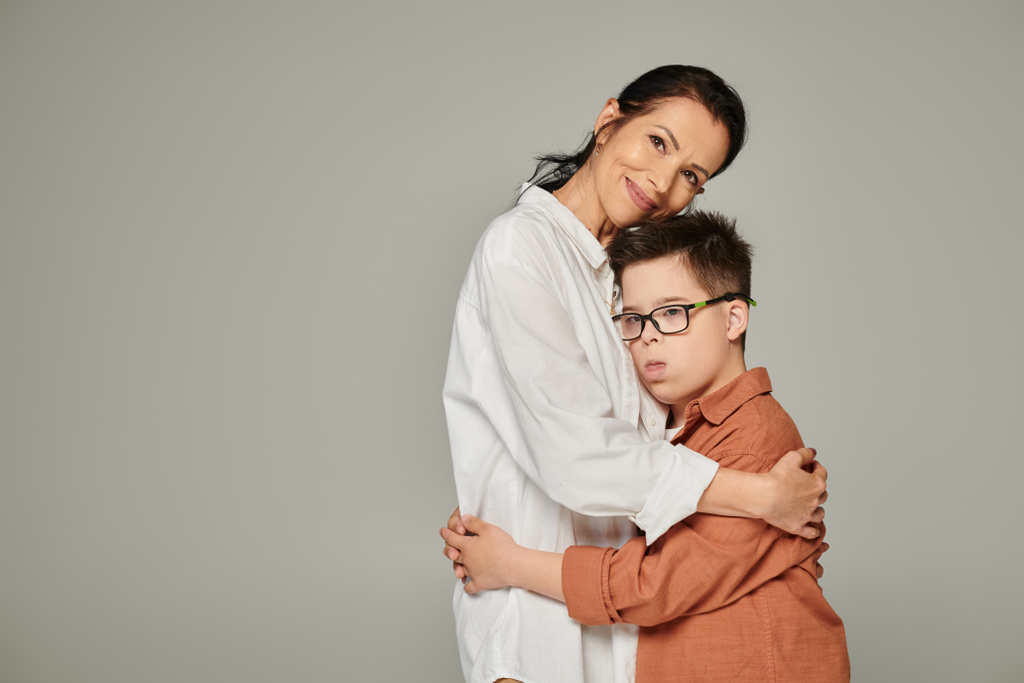joyful middle aged woman hugging son with down syndrome and smiling at camera on grey, banner - Photo, Image