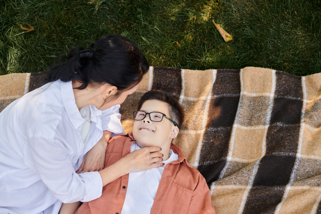 top view of mother near happy son with down syndrome on blanket in park, unconditional love - Photo, Image