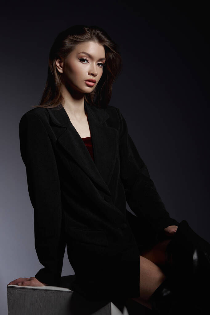 Модная женщина в черных кожаных сапогах и черной куртке, портрет. Длинные волосы, красота, красивые глаза - Фото, изображение