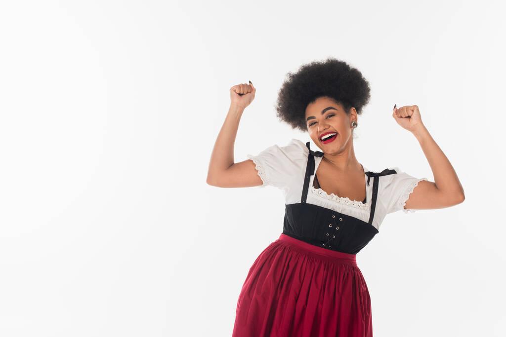 animada garçonete afro-americana em traje tradicional bávaro regozijando e gesticulando em branco - Foto, Imagem