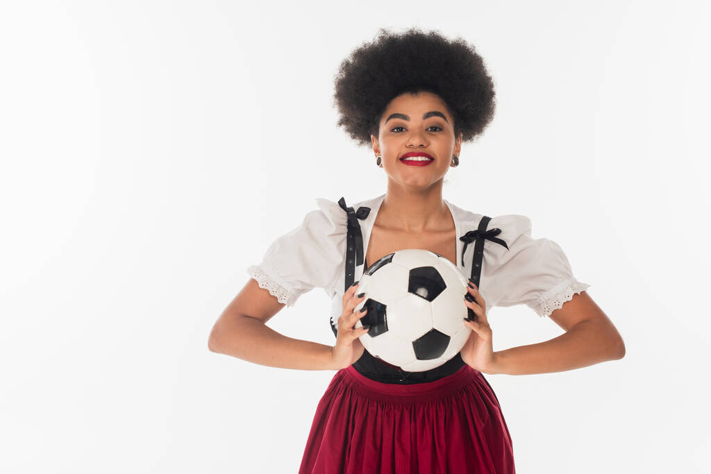 afrikanisch-amerikanische Kellnerin im Dirndl mit Fußballball auf weißem Oktoberfest-Konzept - Foto, Bild