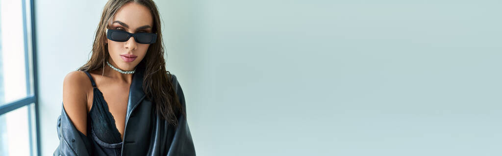 портрет спокусливої жінки в сонцезахисних окулярах, що позує в чорній мереживній білизні та шкіряному пальто, банер - Фото, зображення