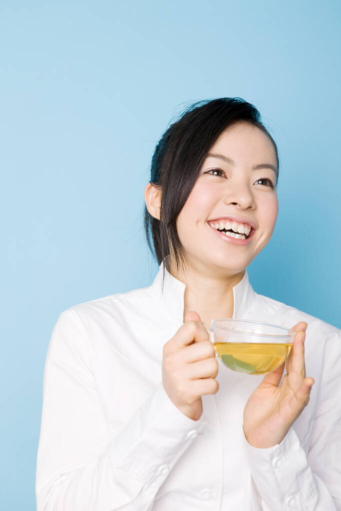 Arka planda çay fincanı olan güzel, genç Asyalı bir kadın. - Fotoğraf, Görsel