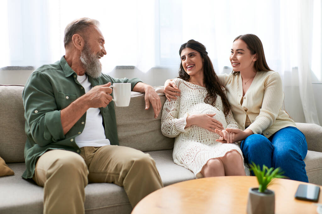 happy cheerful lgbt couple with father of one sitting on sofa and drinking tea, ivf concept - Photo, Image
