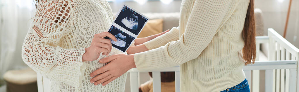 vista recortada de pareja lgbt con las manos en el vientre y ultrasonido de su bebé, concepto ivf, bandera - Foto, imagen