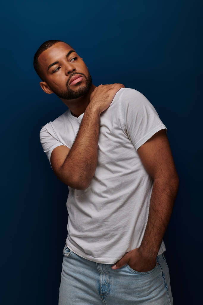 jeune afro-américain en chemise blanche et jeans gesticulant et détournant les yeux, concept de mode - Photo, image