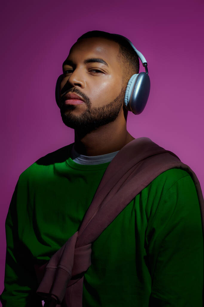 beau modèle masculin afro-américain en sweat-shirt vert avec écouteurs, concept de mode - Photo, image